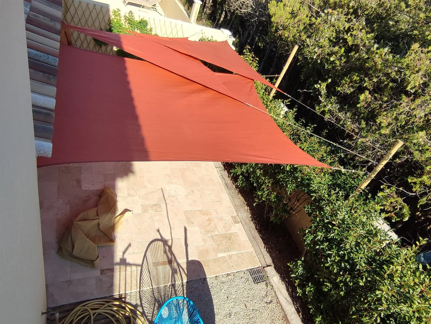 Voile d'ombrage rouge tendue sur des mâts en bambou