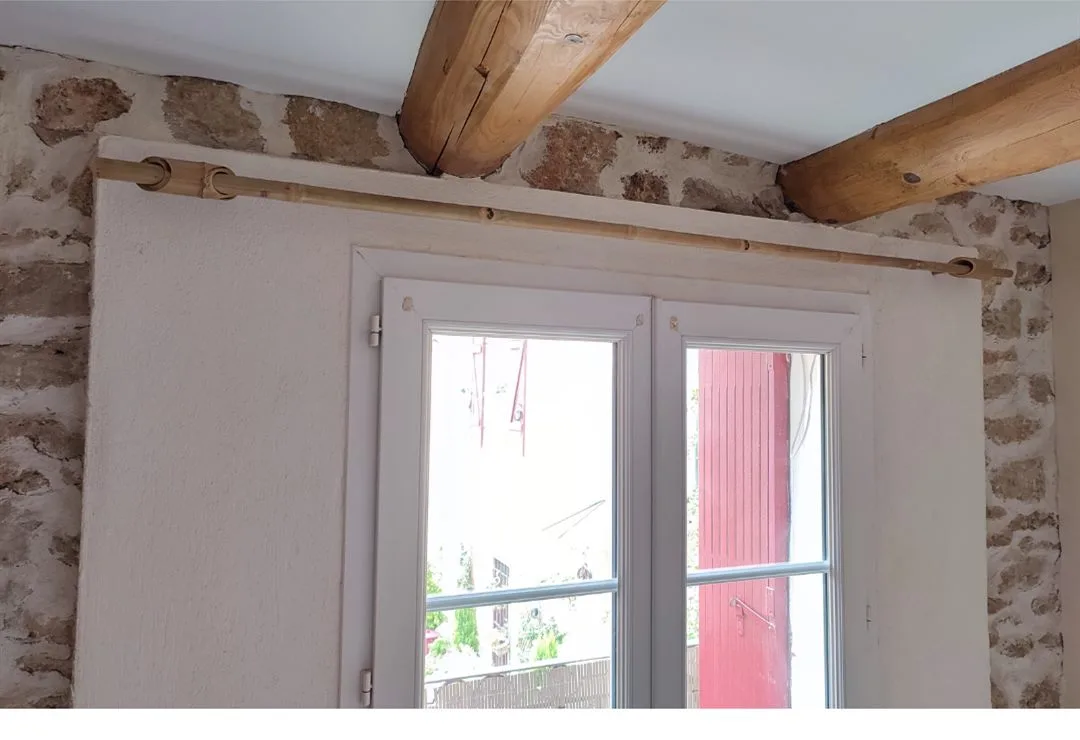 Tringle en bambou au-dessus d'une porte-fenêtre, mur en pierre