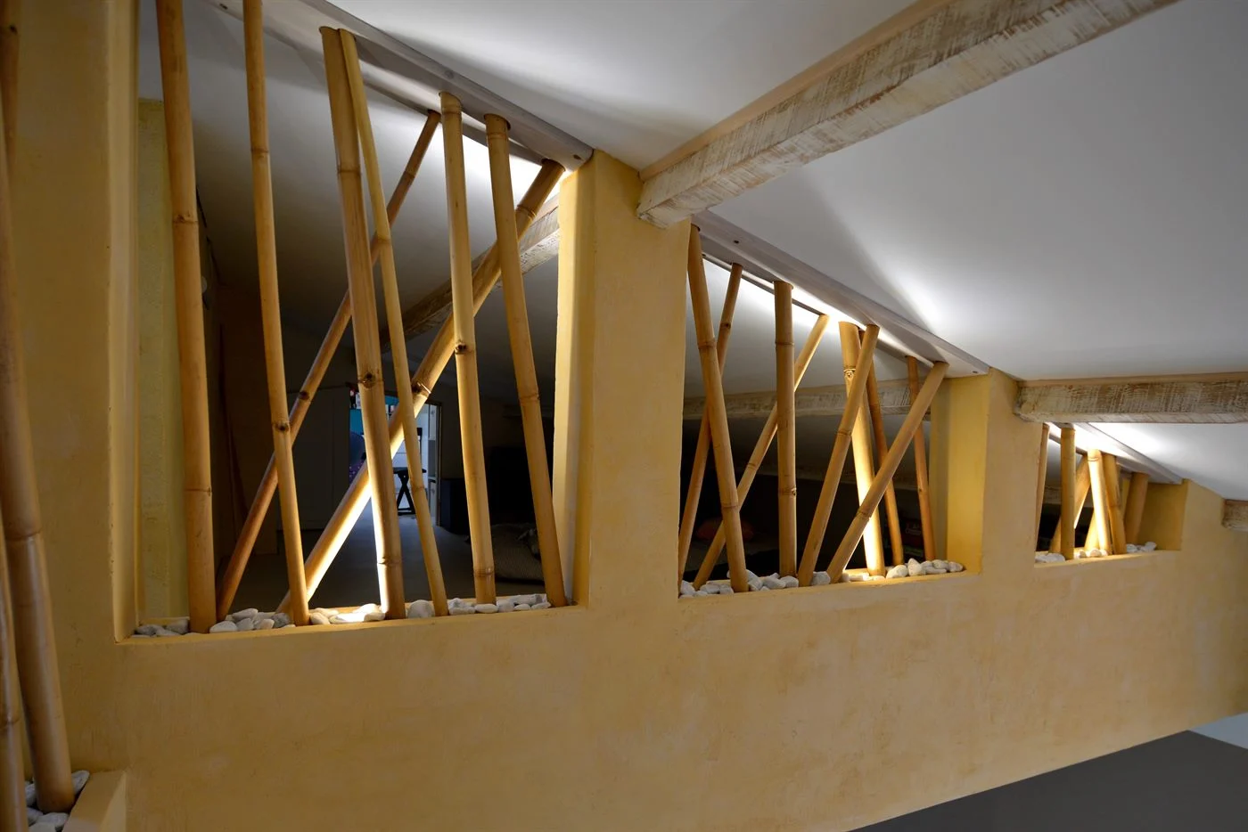 Bambous obliques du garde-corps de la mezzanine, éclairés à leur pied