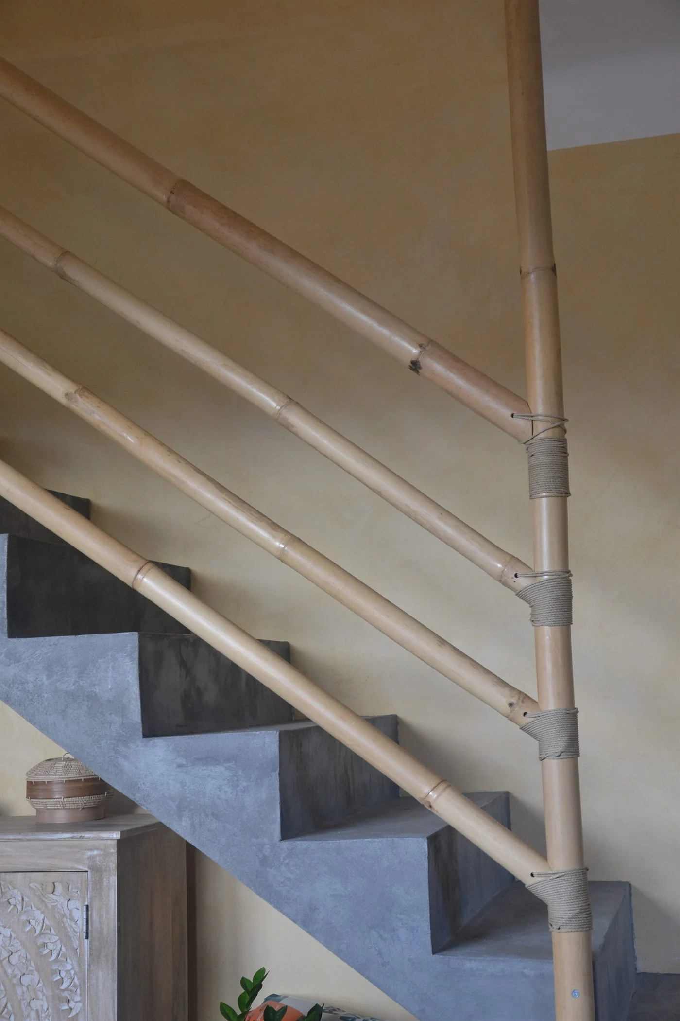 Tronçons de bambou parallèles à la pente de l'escalier, fixés par lashing sur un montant