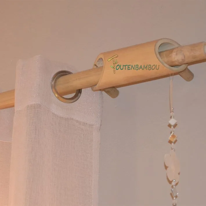 Guide en bambou fixé au mur, tenant la tringle et un rideau à œillets